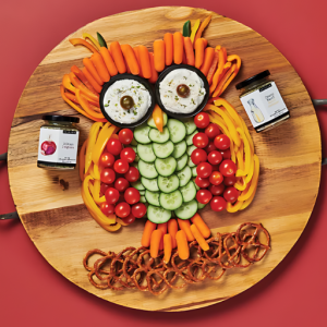 A round wooden tray that is topped with veggies in the shape of an owl. There are 2 jars of Epicure dip mix seasonings also on the tray. One jar of Creamy Ranch and one jar of Epicure's 3 Onion Dip Mix, which is one of the Top 10 products.
